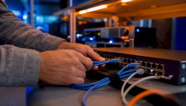 Hands connecting Ethernet cables in cybersecurity lab